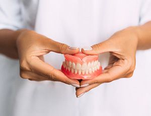 A woman’s hands holding dentures