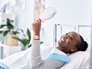 Woman smiling at reflection in handheld mirror