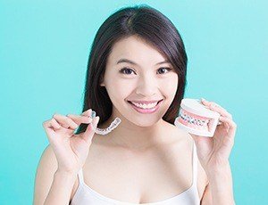 Woman holding ClearCorrect tray and model smile with braces
