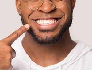 close-up of a man pointing to his smile 