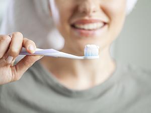 Woman with dental implants in Fayetteville, NY holding her toothbrush