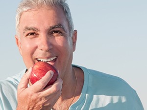 Man with dental implants in Fayetteville, NY eating an apple