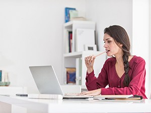 Woman with dental implants in Fayetteville, NY chewing on end of pencil