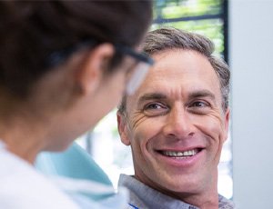 man smiling while talking to dentist 