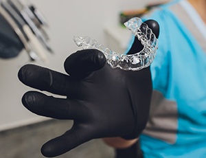Dentist with black glove holding Invisalign aligner