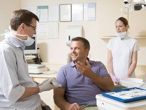 Man in dental chair talking to dentist