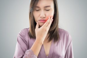 woman holding jaw in pain