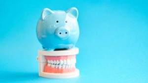 blue piggy bank on top of dentures with blue background