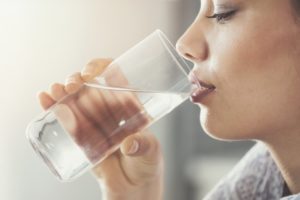 Woman with dry mouth drinking water thanks to Fayetteville dentist
