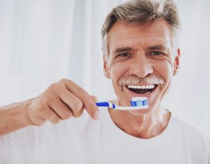 older man brushing his teeth until dentist in Fayetteville reopens