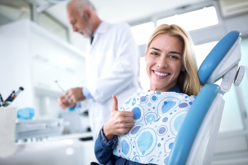 A young female patient giving a thumbs up after seeing her dentist for a checkup