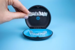 Someone holding an Invisalign tray over its case