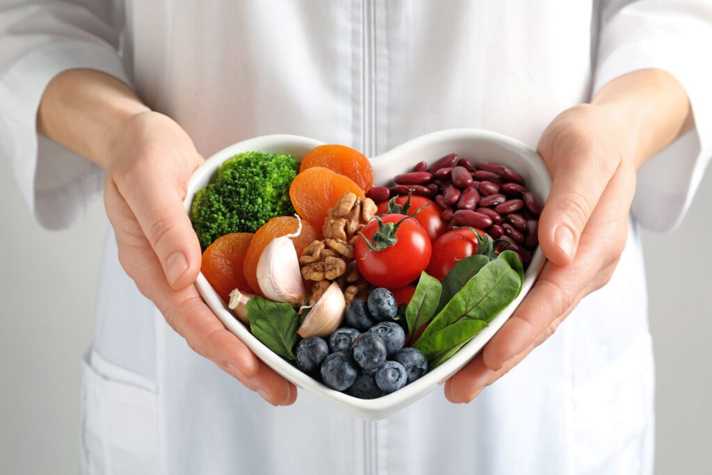 Hands holding heart-shaped bowl full of healthy foods